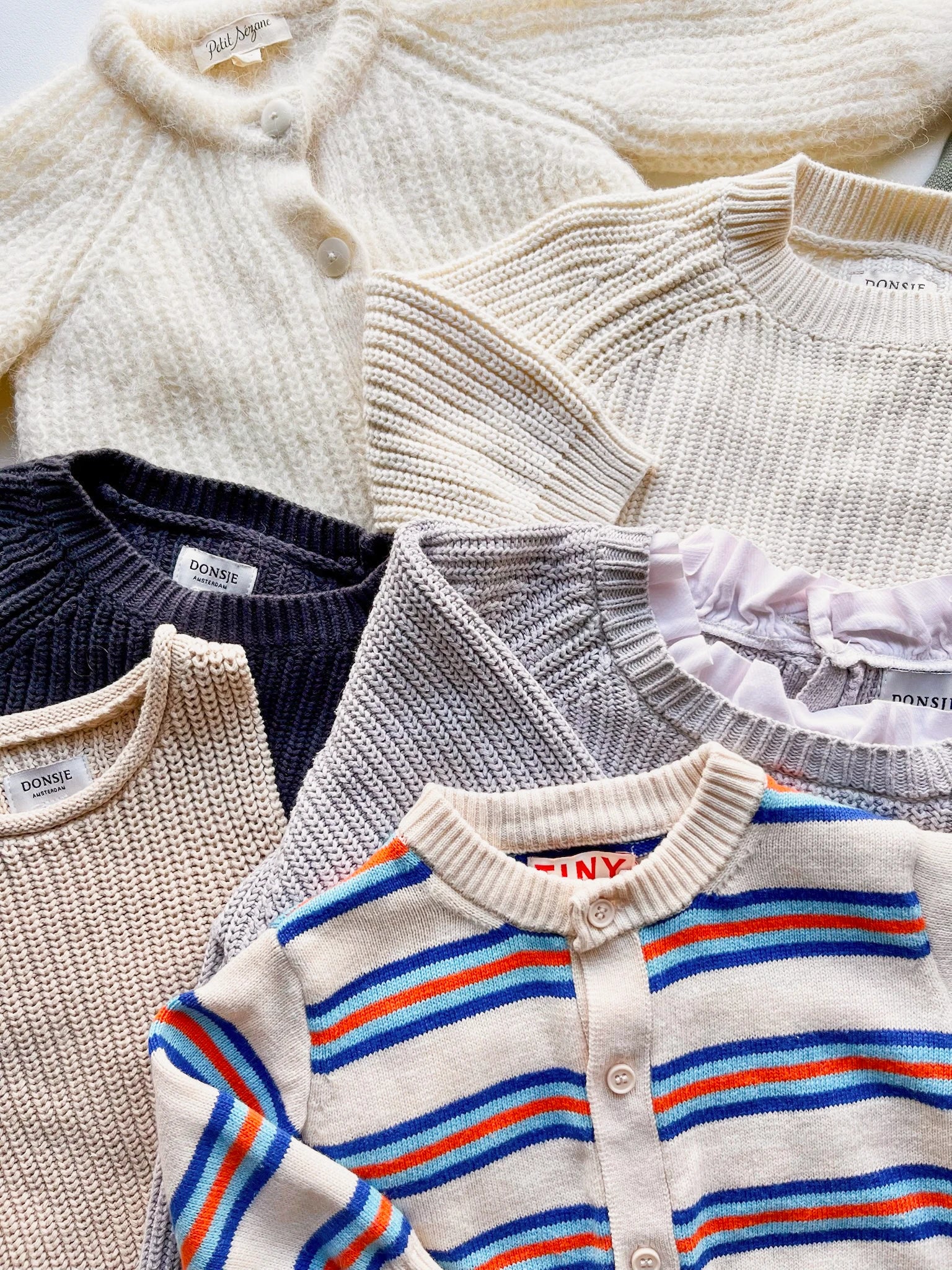 Collection of various knitted sweaters including striped ones.