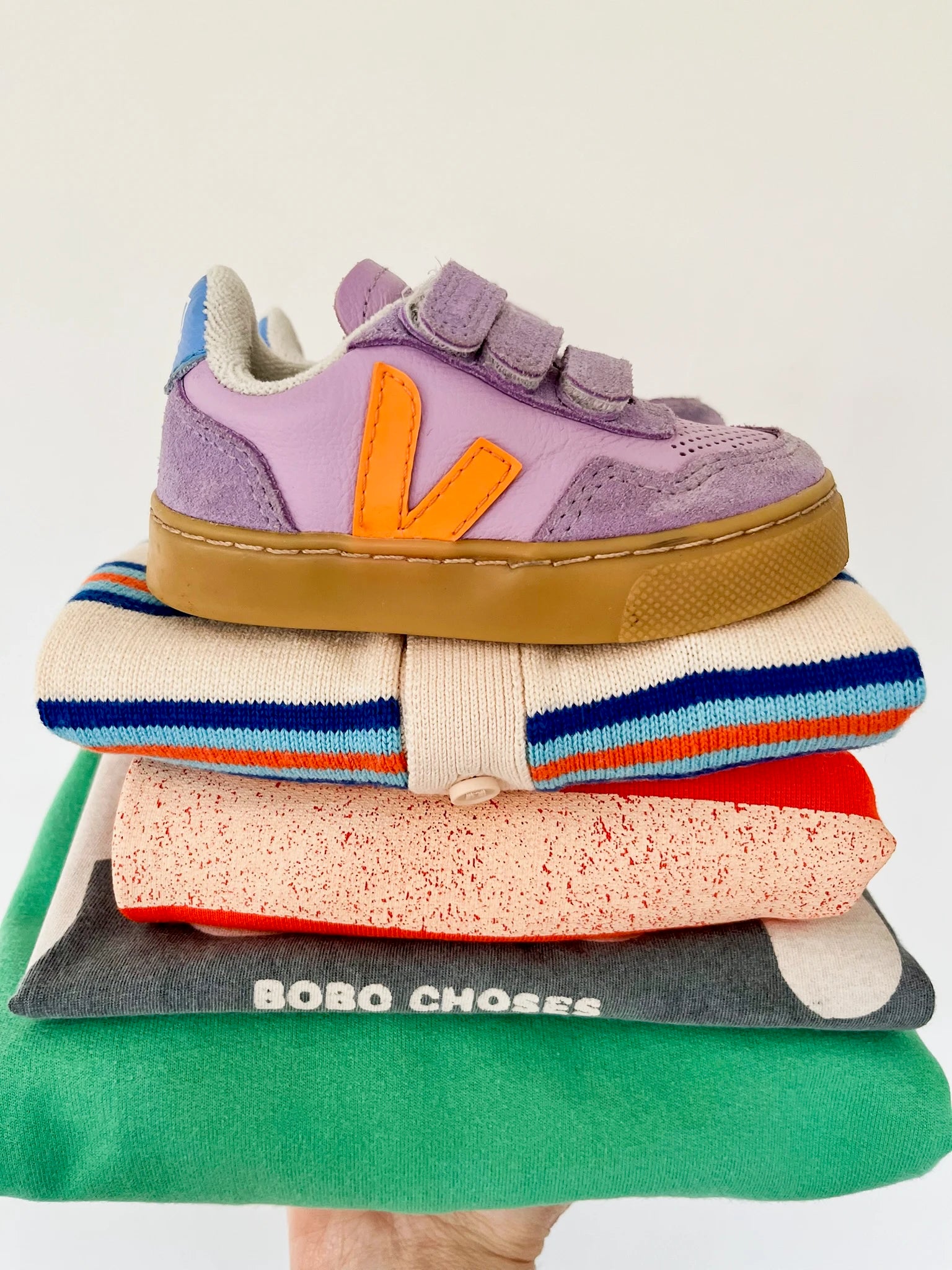 Stack of colorful socks with a purple sneaker on top, featuring the brand 'Bobo Choses'.